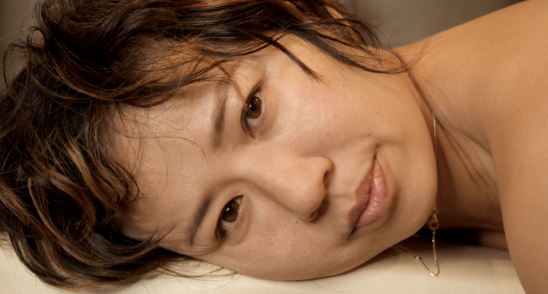 A photograph of the artist, Kim Ye, lying down looking directly at the camera